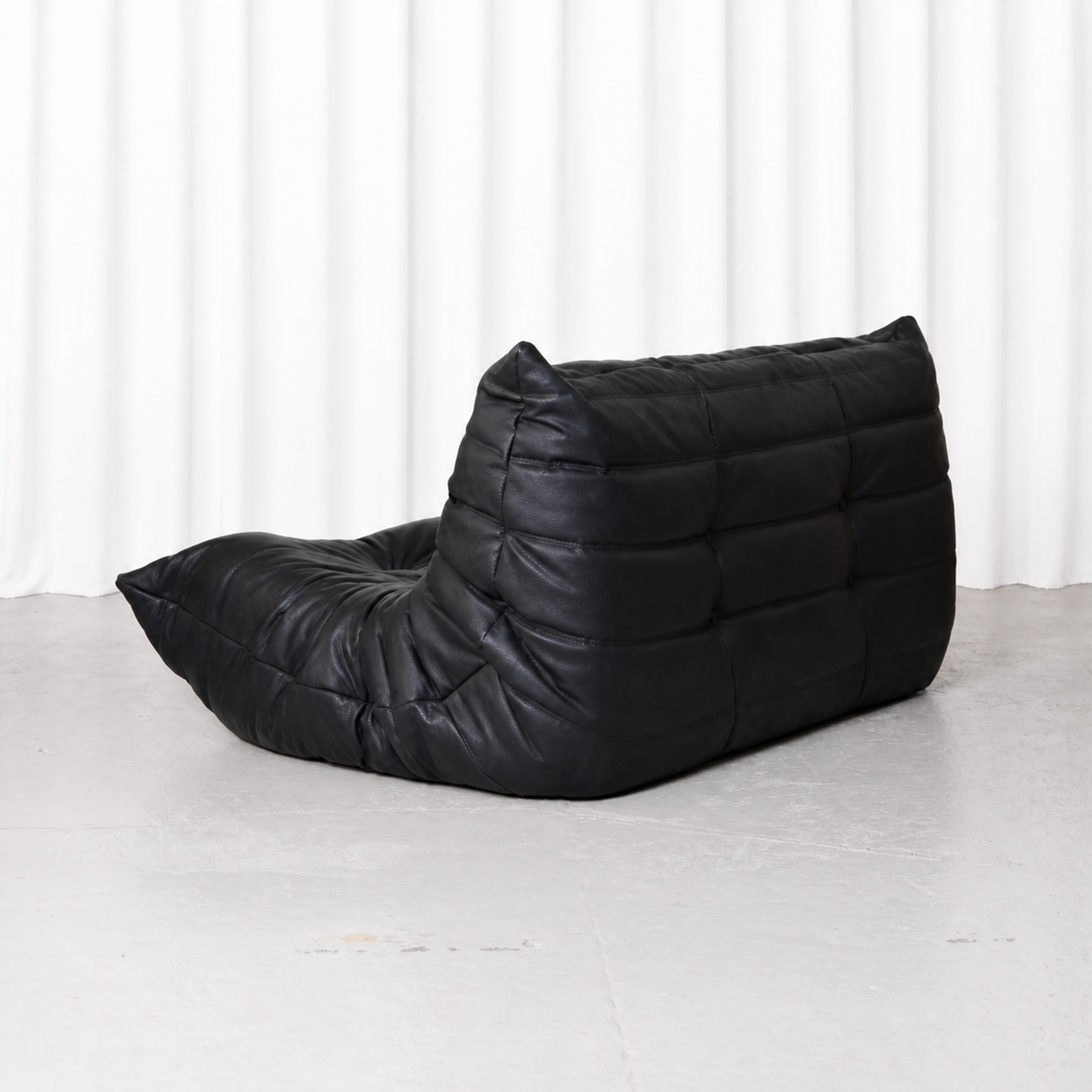 Back three-quarter view of the black Ligne Roset Togo two-seater sofa.