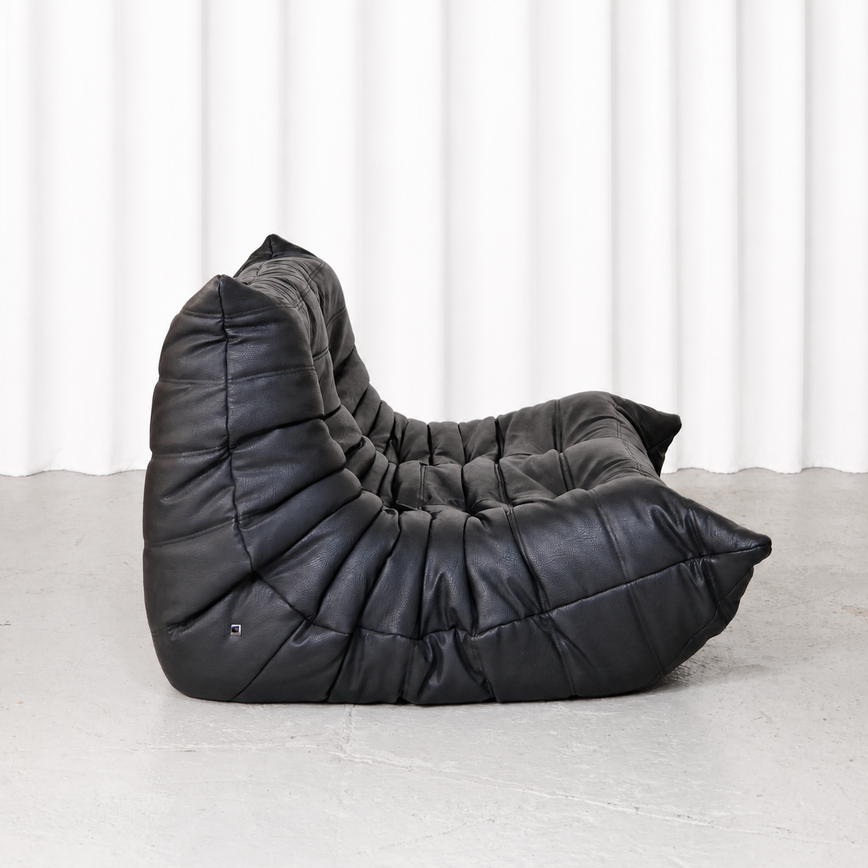 Ligne Roset Togo two-seater sofa in black synthetic leather, side view.