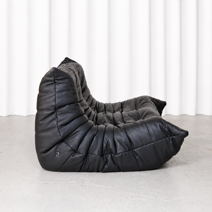 Ligne Roset Togo two-seater sofa in black synthetic leather, side view.
