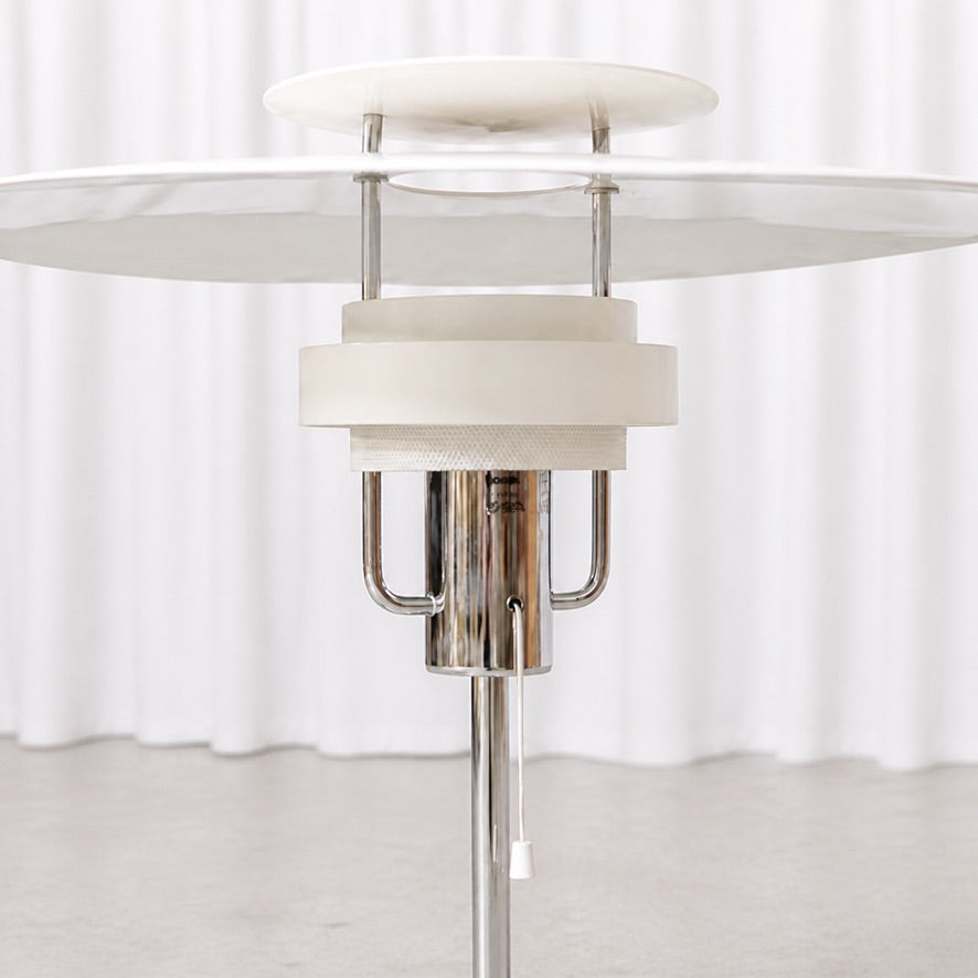 Layered white shade, chrome stem and pull switch detail of the Aurora table lamp