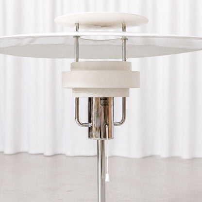 Layered white shade, chrome stem and pull switch detail of the Aurora table lamp