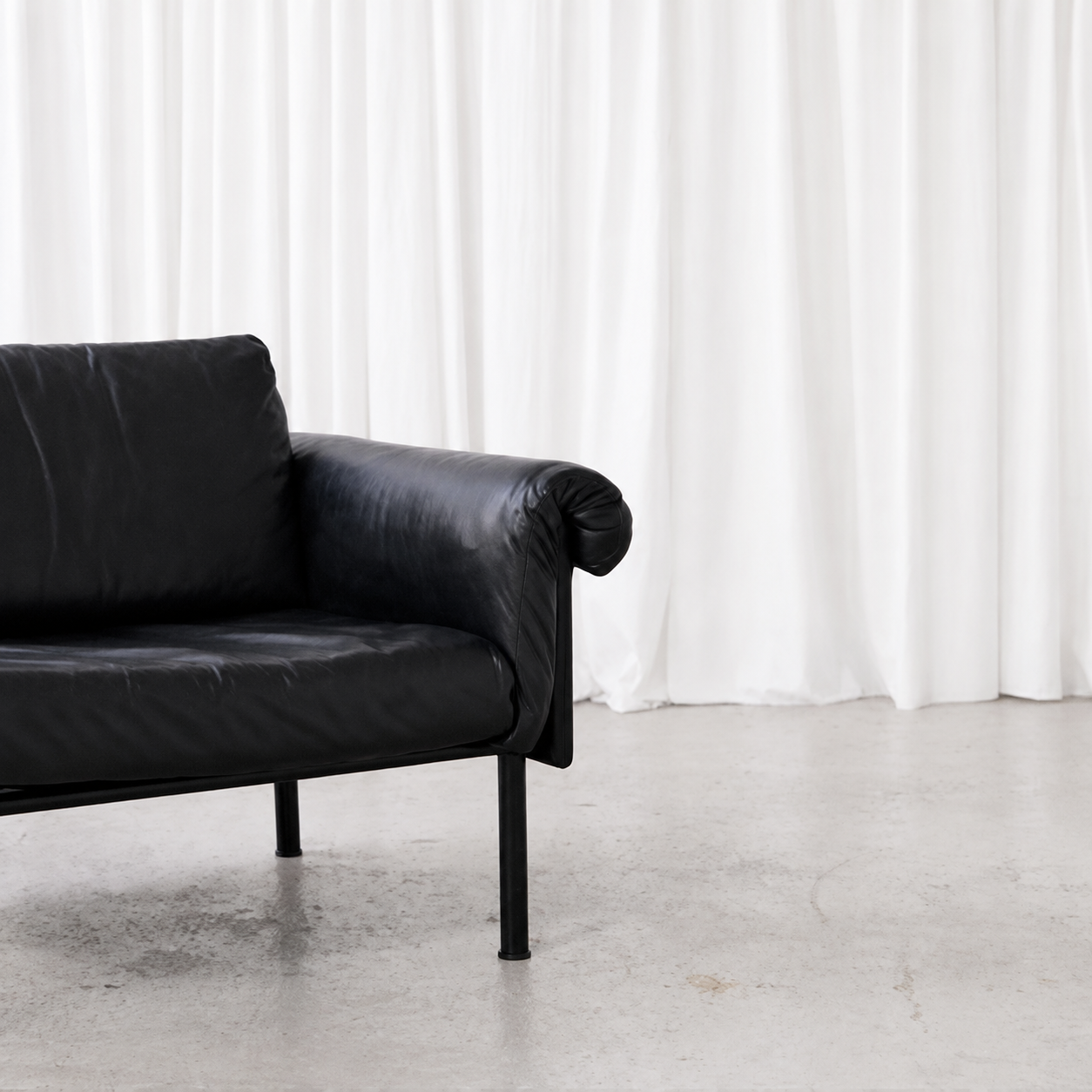 Black leather upholstery and tubular steel frame detail on an Ateljee armchair